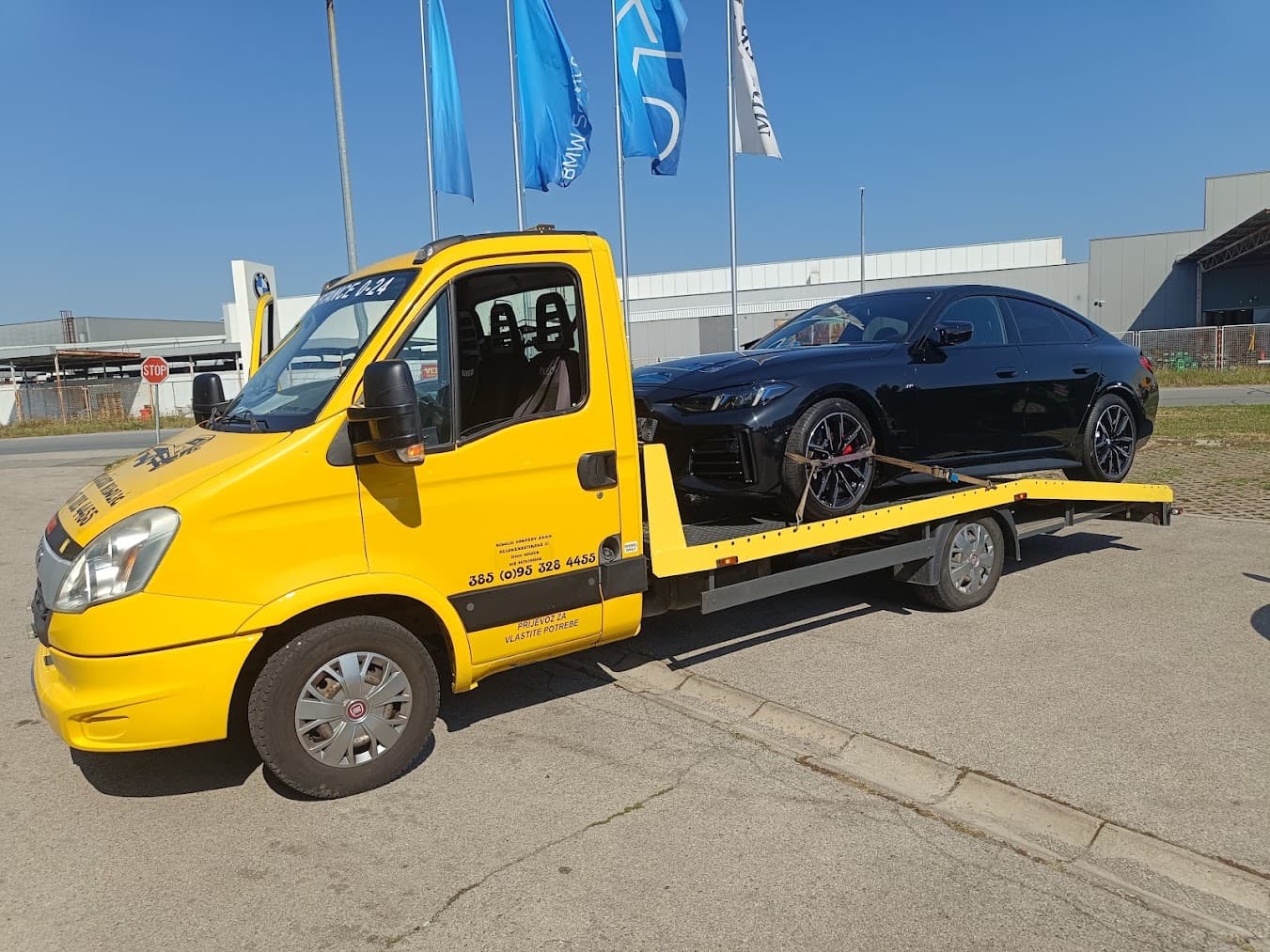 Tow truck loading a car outside a BMW dealership