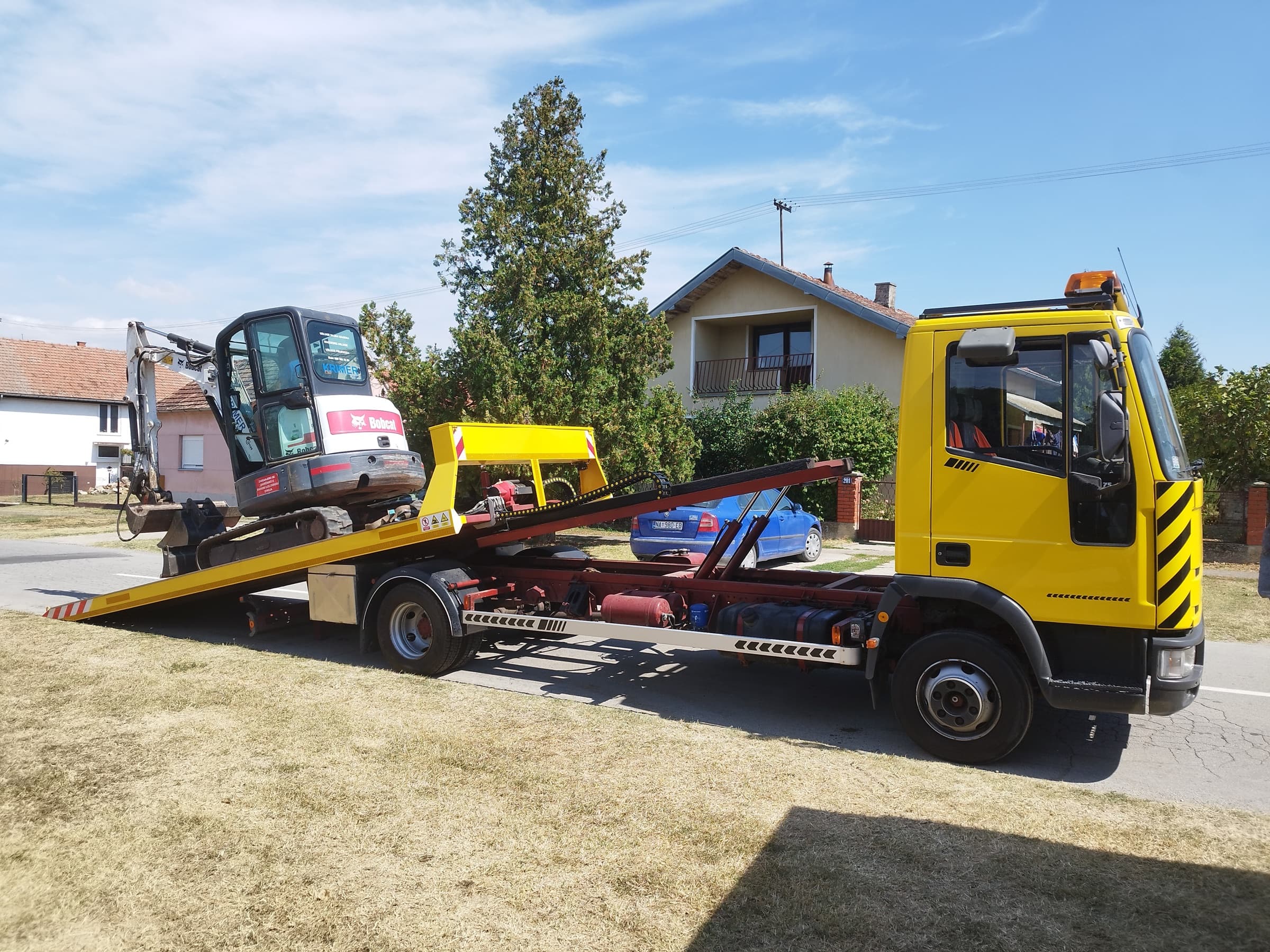 Bobcat mini excavator on a tilted flatbed during loading