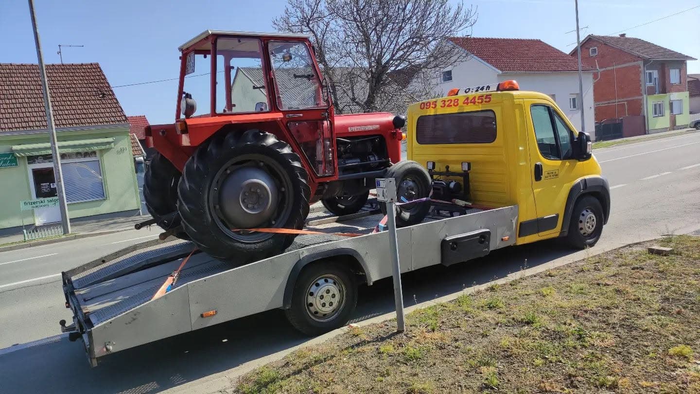 Red tractor loaded on a Nikolić flatbed